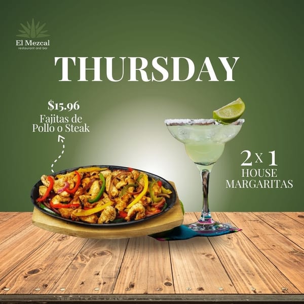 Sizzling chicken or steak fajitas with peppers and onions, next to a margarita on a wooden table.