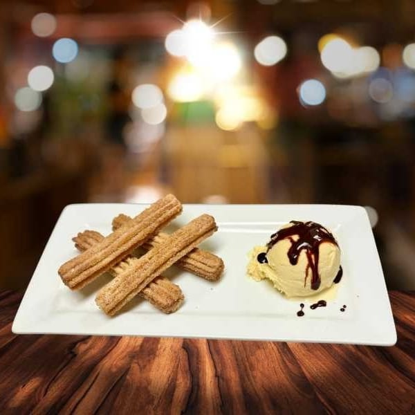 Churros dusted with cinnamon sugar and a scoop of vanilla ice cream with chocolate syrup.